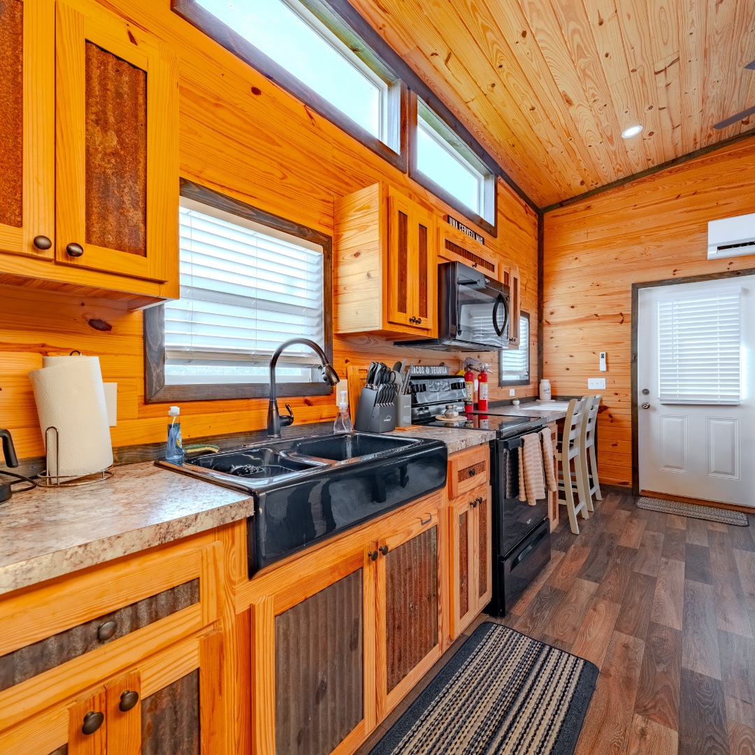 Kitchen of luxury cabin, showing wood paneling throughout and black appliances