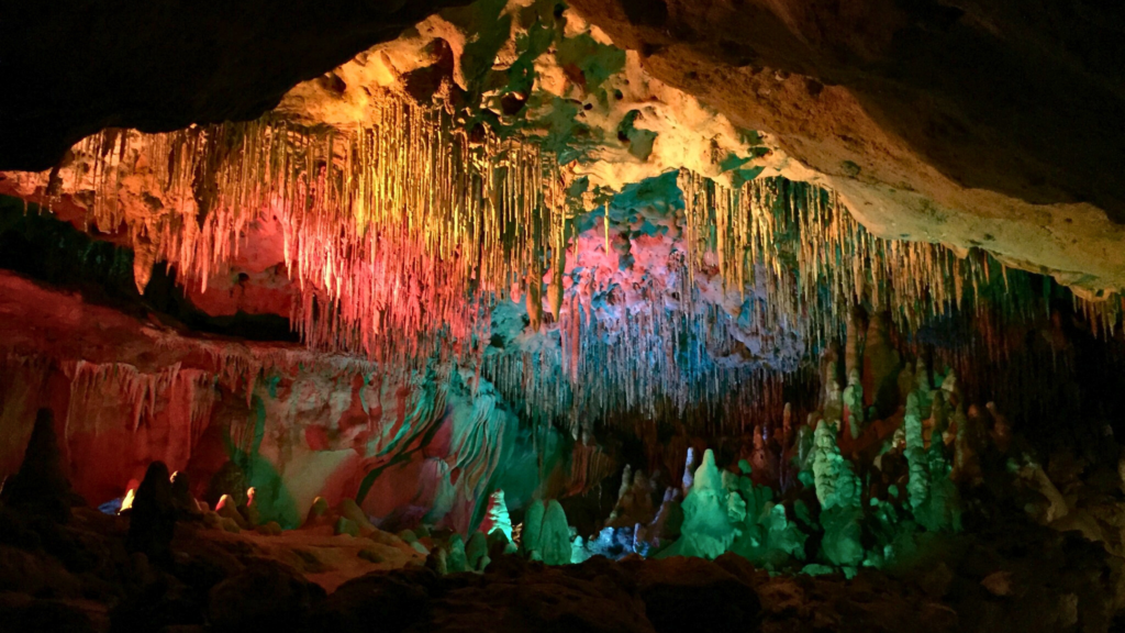 Photo of the limestone caves at Florida Caverns State Park. The caves looks colorful with red, blue, and green pigments on the ceiling of the cave.
